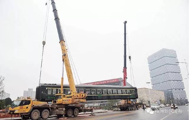 1月24日,在动力谷自主创新园,两辆吊车正吊起一节绿皮火车厢,在机车