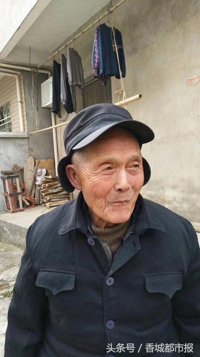 今年81岁,身穿黑色呢子衣,黑色裤子,深桶雨鞋,头戴草帽,手拎个篮子