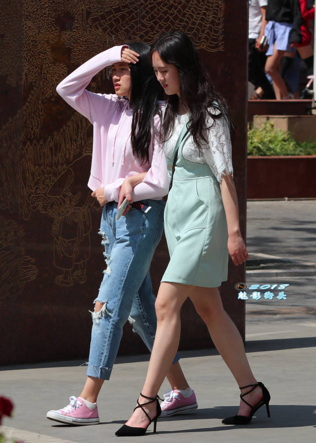 手挽手逛街的两个女孩,穿绿裙高跟的女孩更性感,漂亮