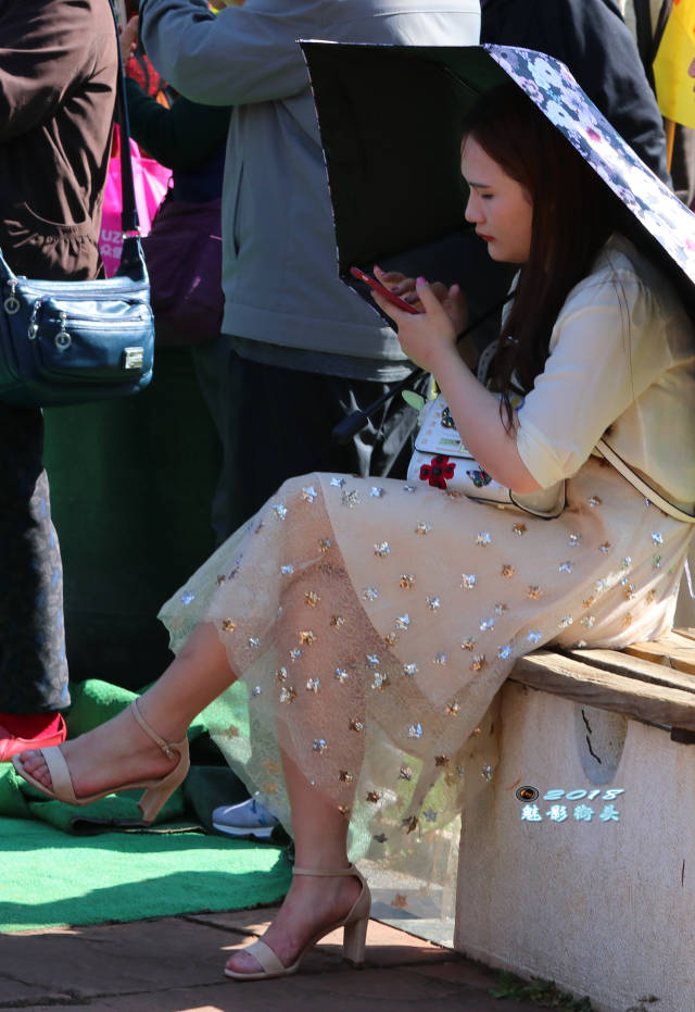 坐在椅子上休息的美女翘着二郎腿,薄纱裙下的美腿非常性感