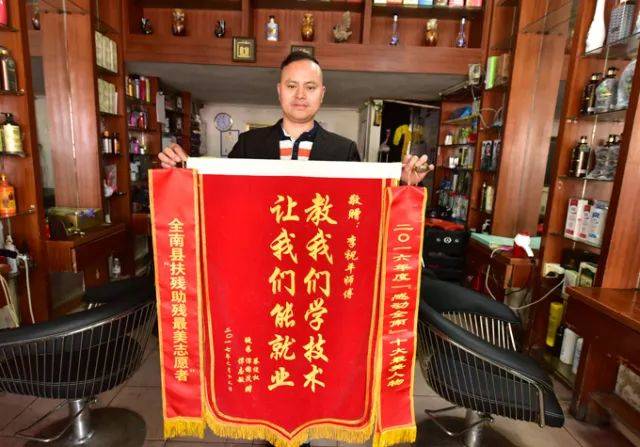 师徒情深,李祝平举着聋哑徒弟送来的谢师恩锦旗.图片来源:江西文明网