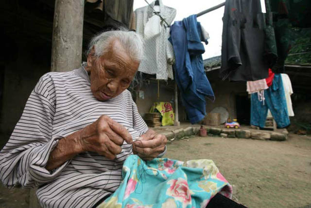 看到睡着的老公,她轻轻地离开房间来到屋外缝补破旧衣服.