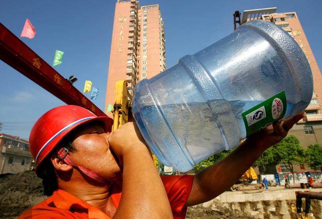 一建筑工地,一工人拿着水桶直接喝水可能是天气太热,也可能是太渴了