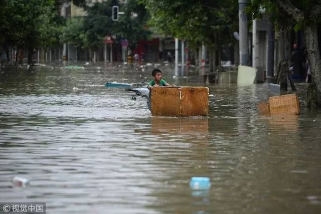 7月12日,成都金堂县,小朋友经过积水的街道.