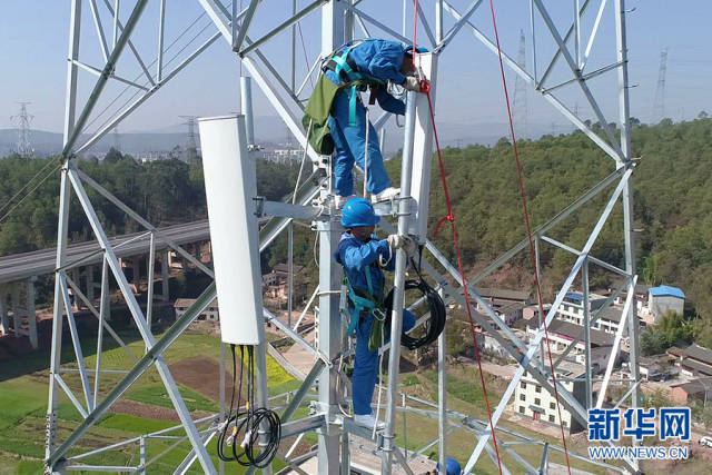 "社会塔"变"通信塔",图为施工人员在电力塔上安装基站设备.新华网发