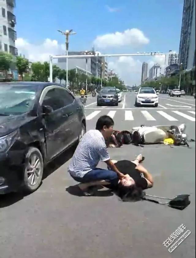 一辆黑色小汽车与电动车相撞 电动车上两人都撞到在地 目前伤势不详!