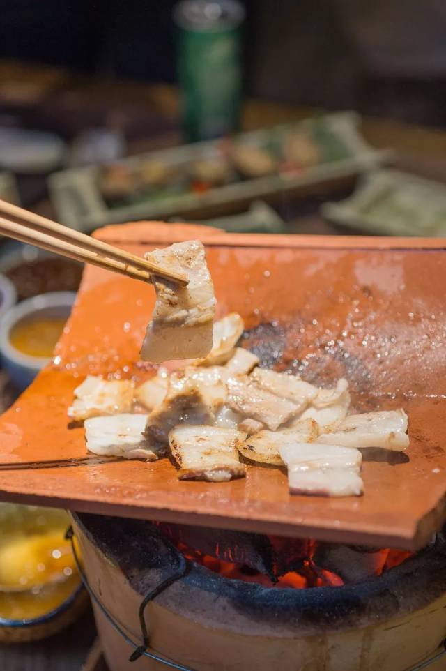 五花肉在瓦片上滋滋冒油,表皮被烤到微焦, 肉汁被紧紧的所在酥皮里