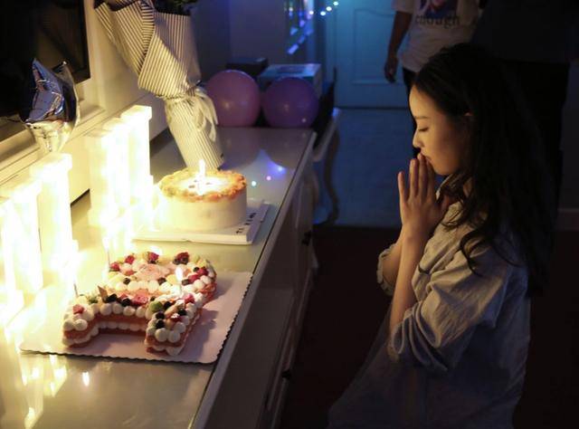 生日蛋糕上插着蜡烛,倪妮对着蛋糕双手合十许愿,样子看起来特别的温婉