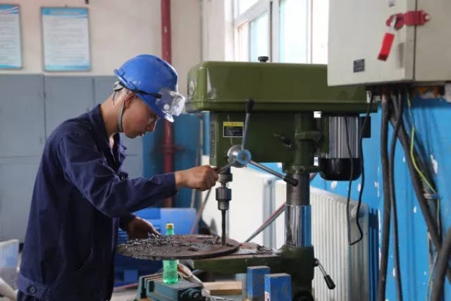 周华健正在台式钻床进行机件加工