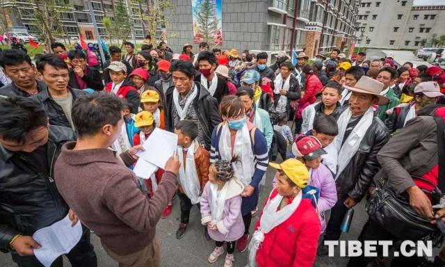 图为新搬迁的群众在排队等候工作人员点名核实门牌号.摄影:赵耀