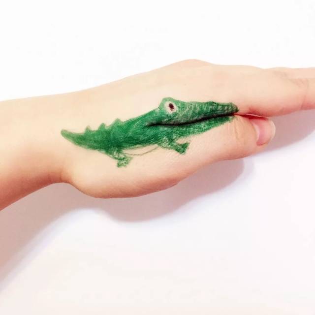 用黑笔给鳄鱼点上一个小豆眼,接着分开大拇指和手掌,如图画上大尖牙.