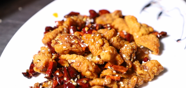 将炸好的酥肉条切成小块儿 油温微热后加花椒,辣椒翻炒,再加入蒜,葱翻