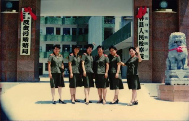 女检察官们身着豆绿色 制服在大门前合影留念