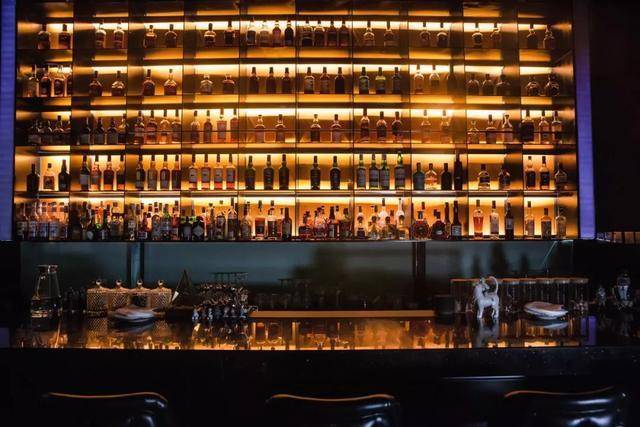 8mm钢板制成的悬空威士忌酒柜中, 整齐摆放着 185款威士忌, 暖黄色的