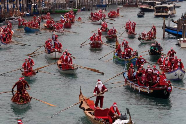 上,人们装扮成圣诞老人,划着贡多拉小船参加传统的圣诞水上巡游活动