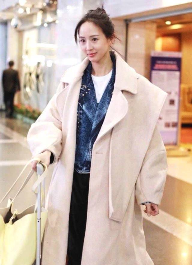 张钧甯走机场示范冬季穿搭,一身米白色的呢子大衣很抢眼,大衣的版型