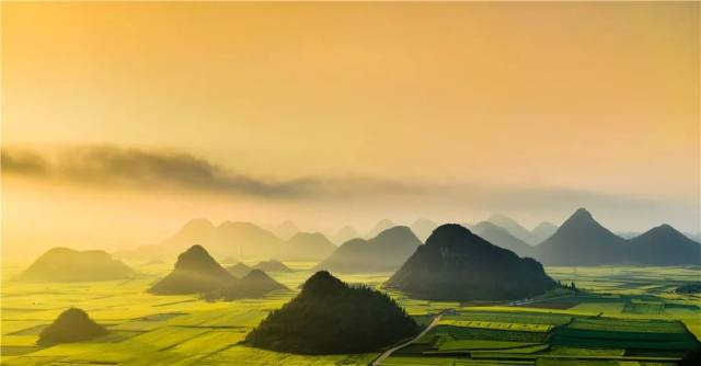 頃刻間,太陽從東方升起,流霧散去,一座座小山如同身披金袍現身,在地上