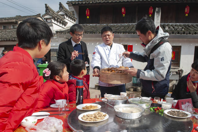 余姚市的家庭与当地村民一起品尝齐家长桌宴,参与写福字等民俗活动,在