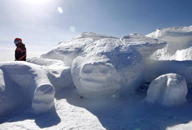 在崇礼太舞滑雪场山顶,滑雪爱好者和雪雕的生肖猪合影