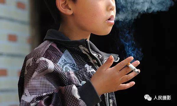 2012年5月20日,湖南新邵,一位小孩学着爷爷的样子吸烟 潇湘之子 摄