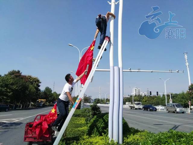 工人们正忙着在沿街路灯杆上悬挂国旗