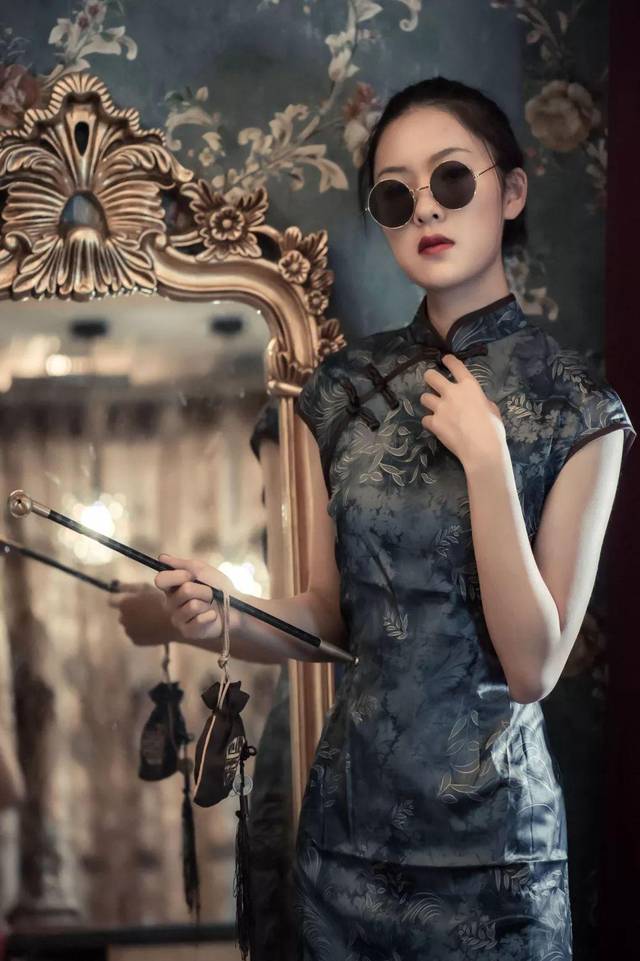 手持烟斗钱袋,不羁又有些倦怠的神情,搭配深色素净旗袍,多了一丝霸气