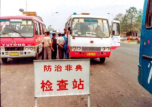 2003年老照片:抗击非典,防疫人员在长途客车上登记检查旅客