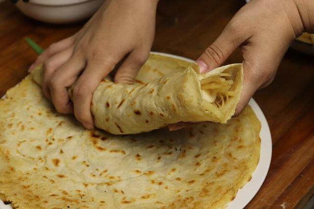 然后我们将烙好的饼上面放入炒好的土豆丝,再加上一颗大葱,这样给它卷