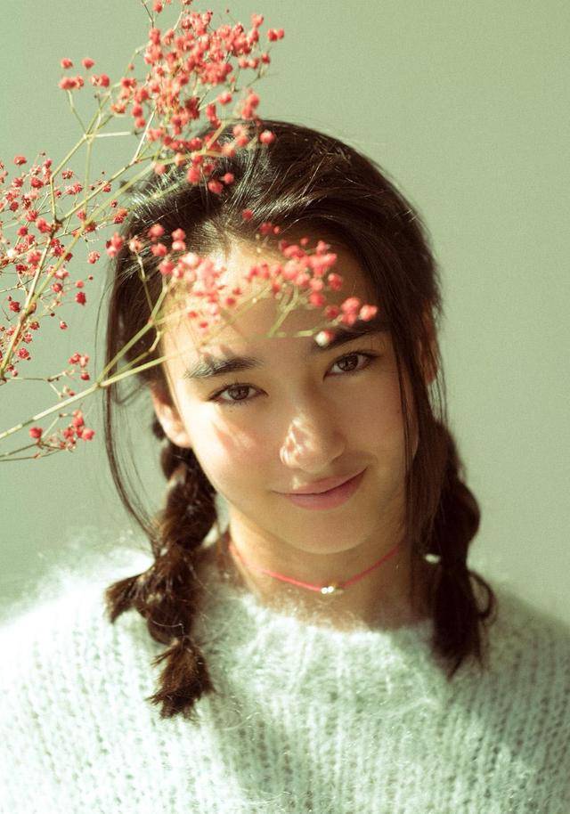 照片中,李宛妲或身着白色针织毛衣,将头发扎成双麻