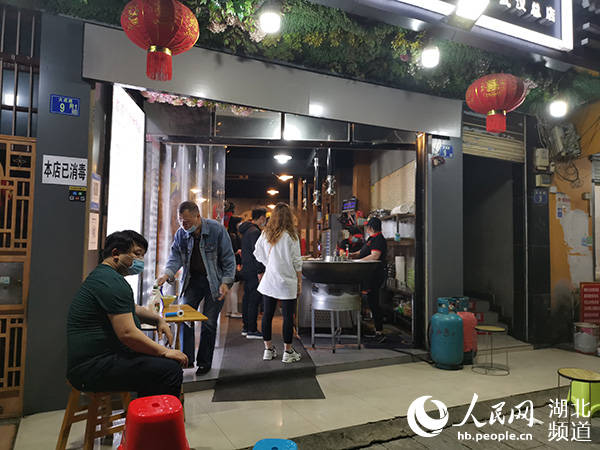 武汉武昌区大成路上一家牛杂火锅店恢复堂食,工作人员在门口值守,要求