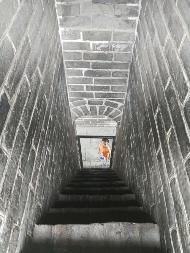 在左边山峰上的地12座敌楼上,有一段十分陡峭的台阶,一个小朋友正跃跃